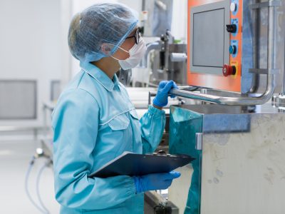 caucasian factory worker in blue lab suit check readings of machine, look at control panel